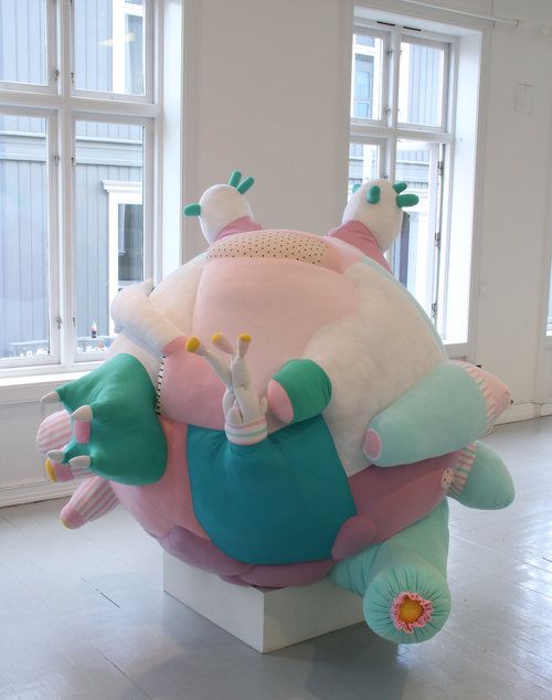 a large stuffed animal sitting on top of a white pedestal in front of two windows