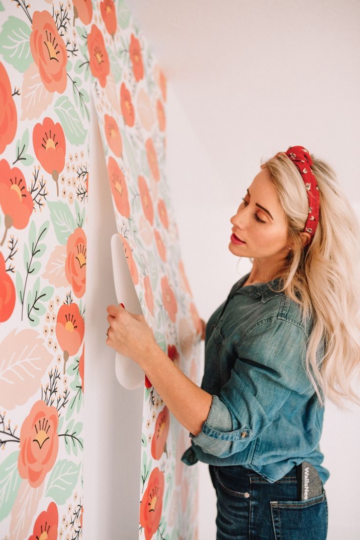 a woman is painting a wall with flowers on it and she has her hair pulled back