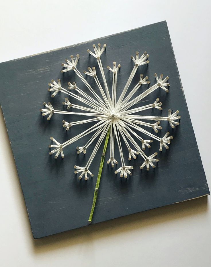 a dandelion made out of sticks sitting on top of a piece of wood