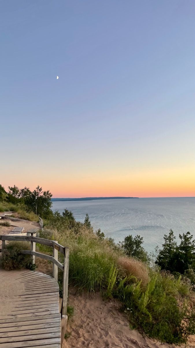 a wooden walkway leading to the beach at sunset