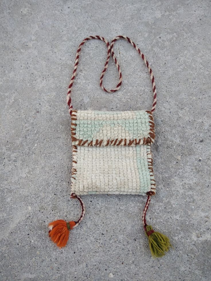 a small white and brown bag with tassels on the handle sitting on concrete