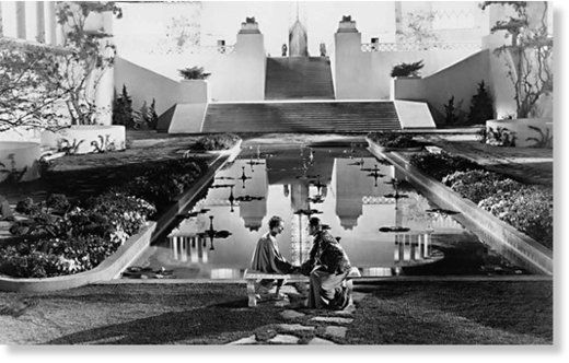 black and white photograph of two people sitting in front of a building