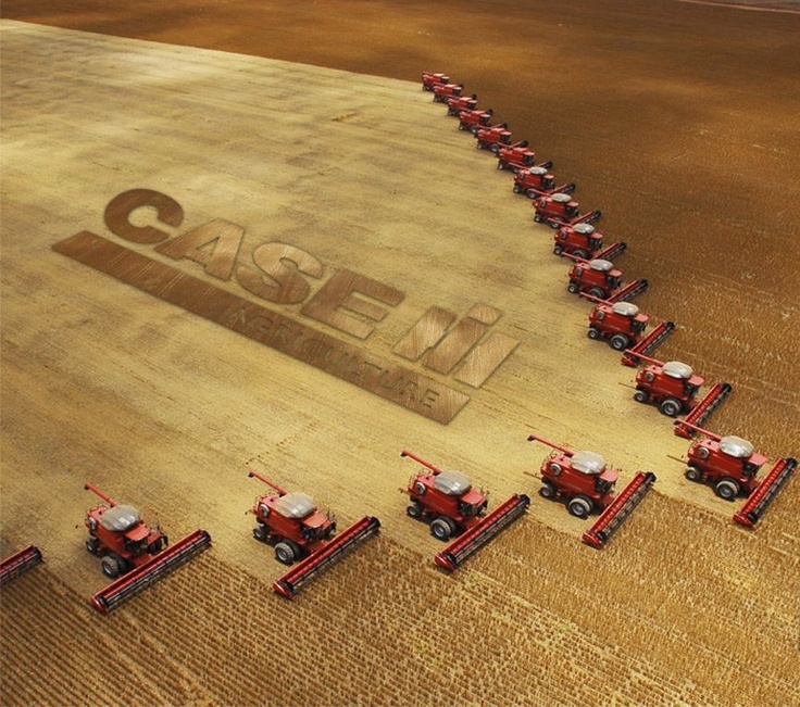 a group of red farm tractors driving down a field next to a sign that reads, friends don't let friends drive green tractors