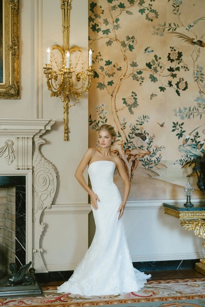 a woman in a wedding dress standing next to a fireplace