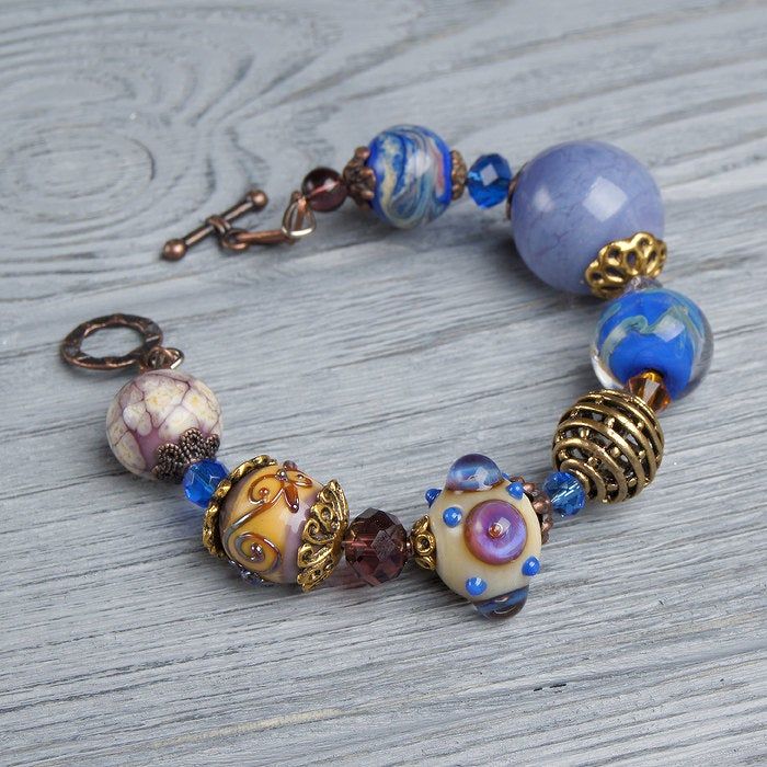 "This Lavender boho bracelet bracelet is a perfect gift for women. It's very tender and unique! This lampwork bracelet fits a 15.5-16.5cm (6.1\"-6.5\" inch) diameter wrist. If you need bigger or smaller size bracelet, please, write me the diameter of your wrist when making an order. Dimentions: 21cm. Materials: artist lampwork beads, metal and glass beads, metal fittings. Colors used: blue, lavender, lilac. Please, note, each lampwork bead is made by hand and may differ slightly. All the photos European Beads Bracelet, Bohemian Blue Czech Glass Bracelets, Artisan Beaded Glass Bracelets, Artisan Glass Beaded Bracelets, Bohemian Czech Glass Faceted Beads, Bohemian Czech Glass Bracelets With Spacer Beads, Bohemian Bracelets With Spacer Beads For Gift, Bohemian Bracelets With Spacer Beads As Gift, Bohemian Crystal Bracelet With Faceted Beads As Gift