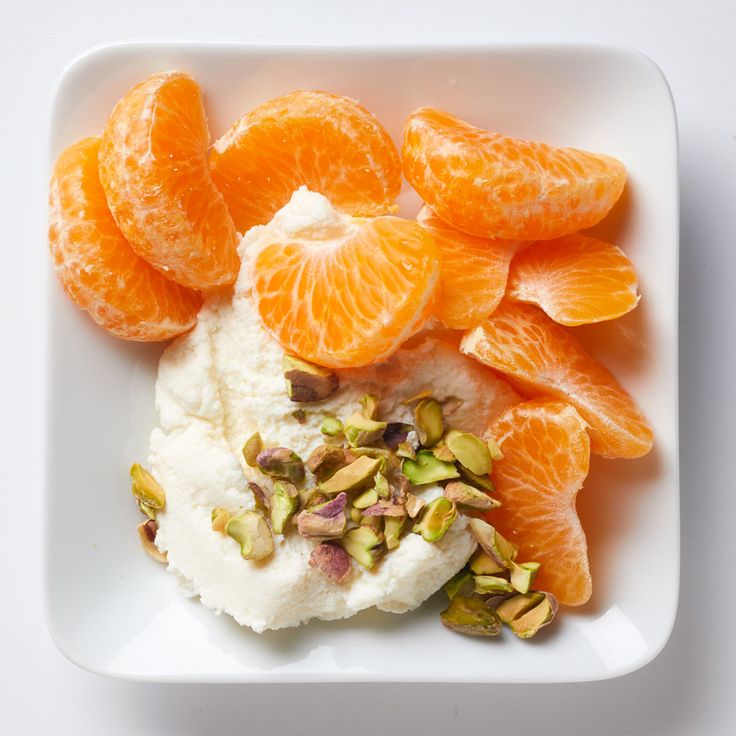 a white plate topped with orange slices and whipped cream covered in pistachio seeds