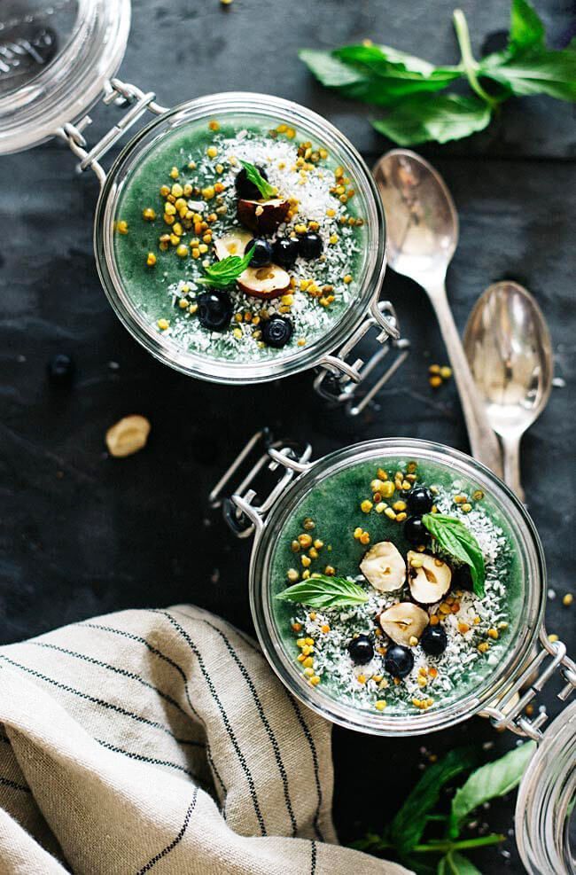 three glasses filled with food sitting on top of a black table next to spoons