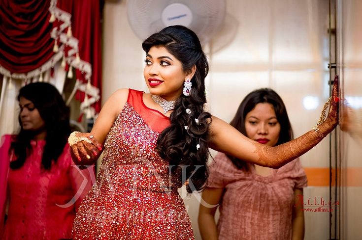 a woman in a red dress standing next to another woman with her arms out and one hand on her hip