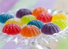 a glass bowl filled with colorful candies on top of a striped tablecloth covered table