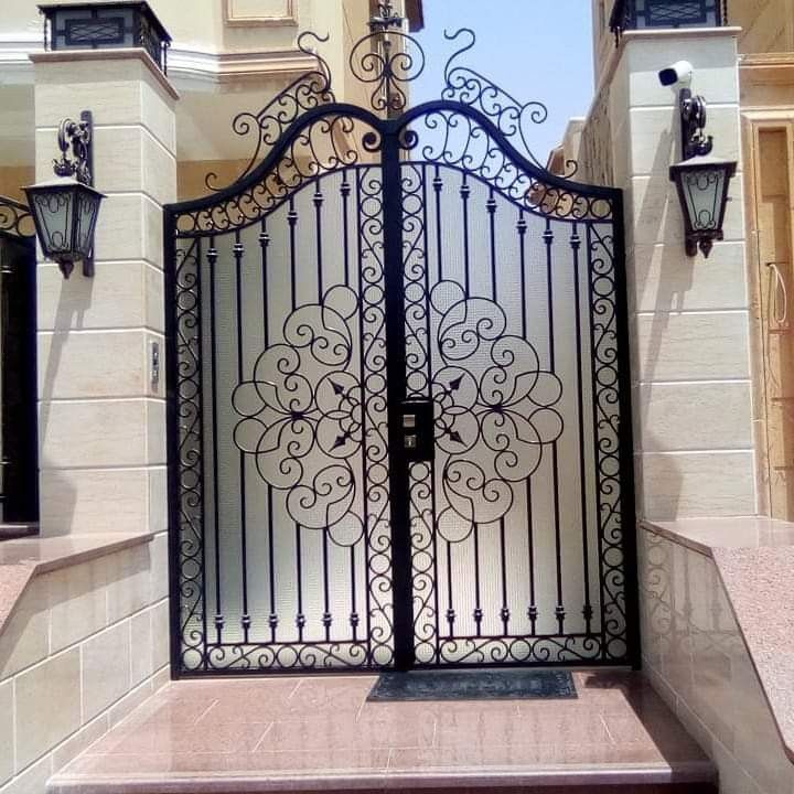 an ornate iron gate is shown in front of a building with two lights on each side