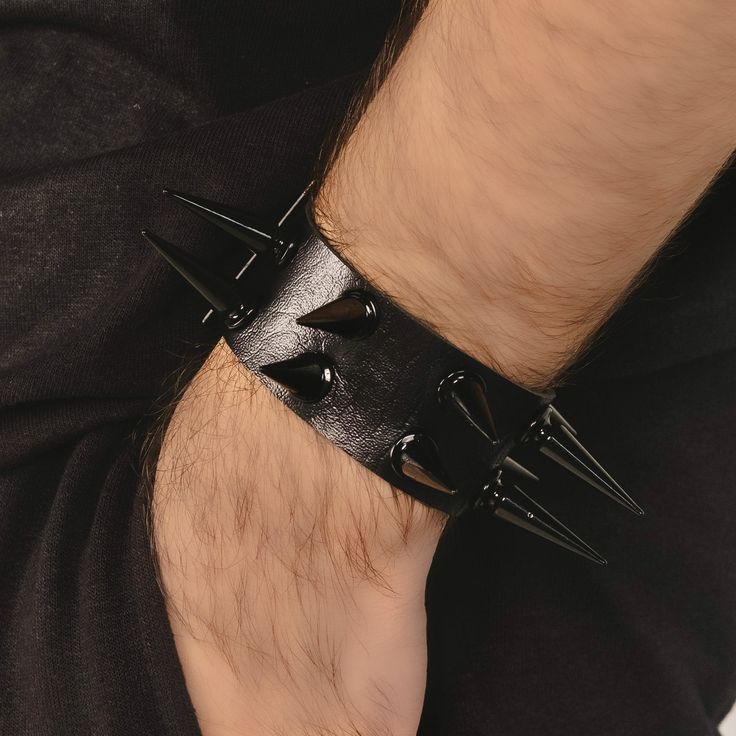 comfortable design. It measures 10 inches in length and 1.5 inches in width, made from soft black leather with adjustable metal buckle, adorned with 10 glossy black alloy metal studs that stick out 1 inch. Edgy Adjustable Wristband With Wrist Strap, Adjustable Edgy Wristband With Wrist Strap, Adjustable Black Punk Wristband, Adjustable Leather Punk Wristband, Black Punk Leather Bracelet Fashion Accessory, Trendy Adjustable Spiked Bracelets, Black Punk Style Leather Bracelet, Black Punk Bracelets For Festival, Punk Leather Bracelet With Studs For Festivals