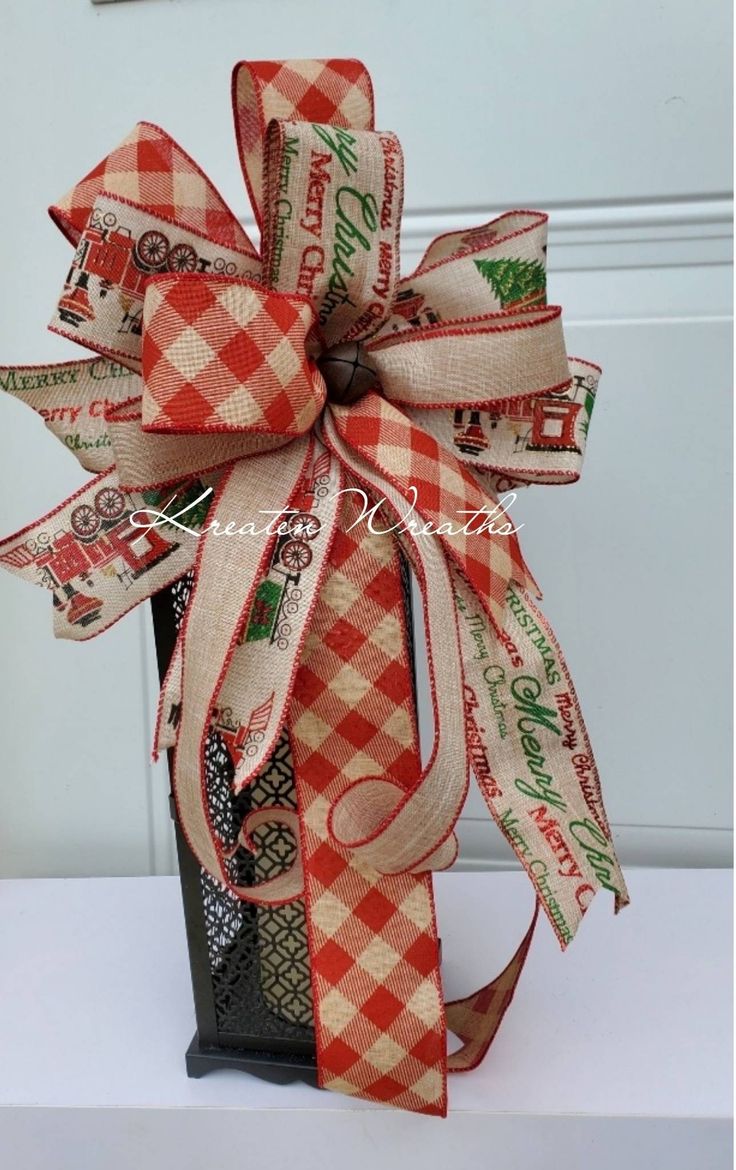 a red and white checkered bow on top of a black box with ribbon around it