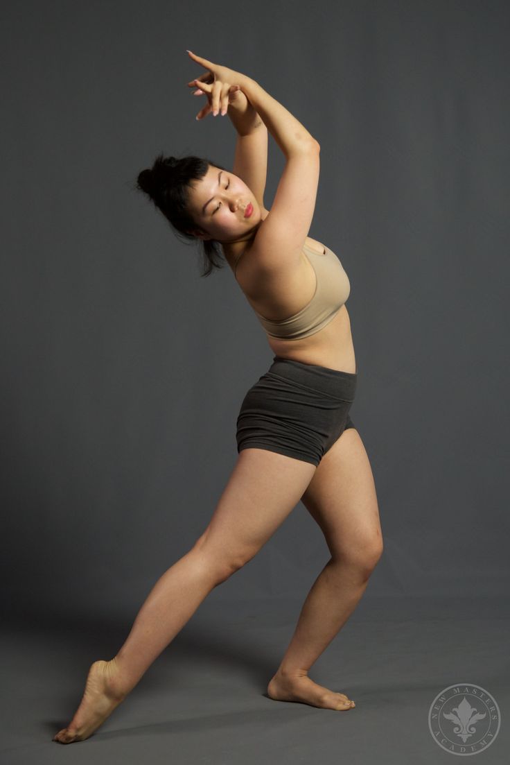 a young woman is posing with her arms stretched out in front of her body and hands behind her head