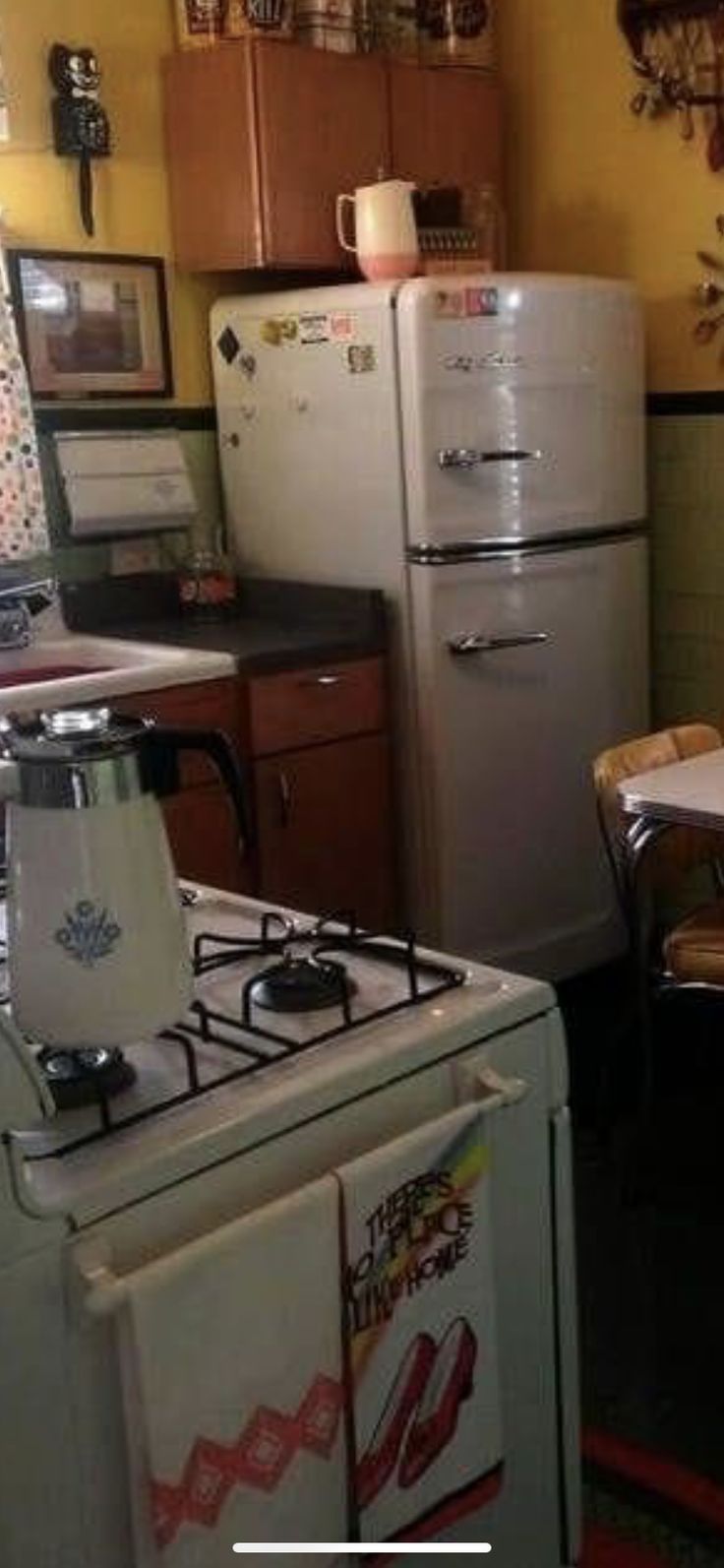 a kitchen with an old fashioned stove, refrigerator and dining room table in the background