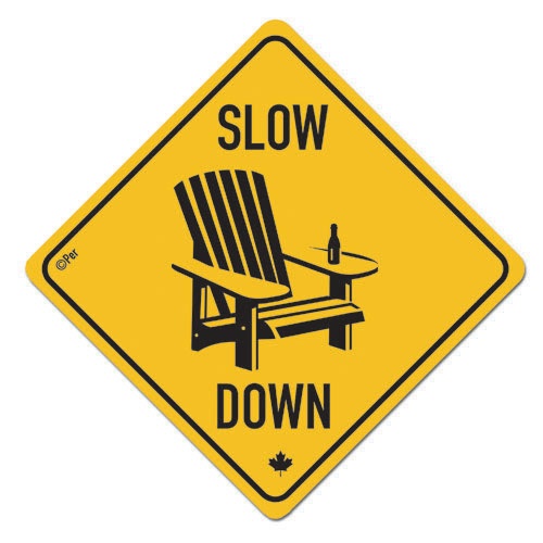 a yellow and black sign that says slow down with a chair on it's side