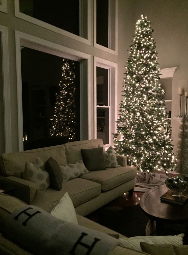 a living room filled with furniture and a lit christmas tree in the window sill