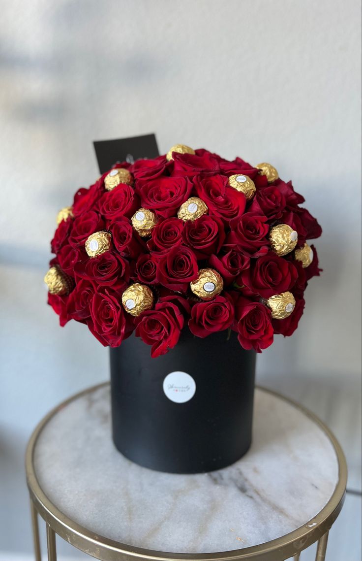 a black box with red roses and chocolates in it sitting on a marble table