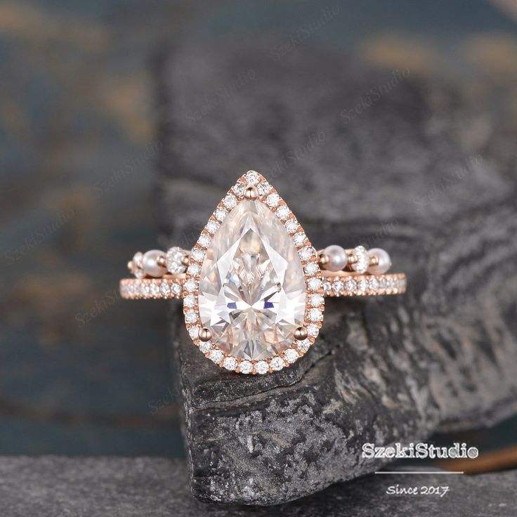 a pear shaped diamond ring on top of a rock