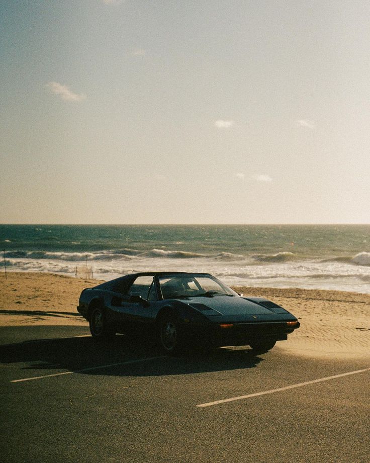 a car is parked on the beach next to the ocean