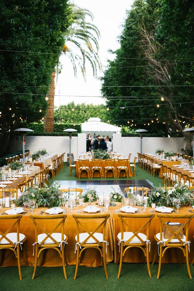 an outdoor dining area with tables and chairs set up for a formal function in the garden