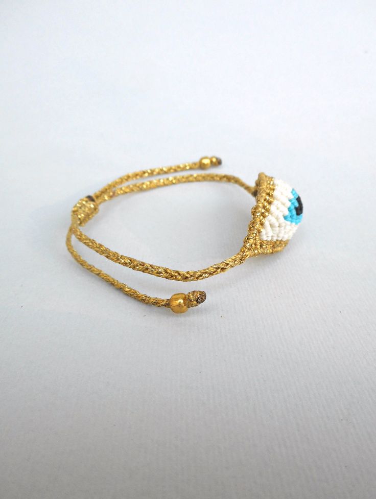 Evil eye Gold Macrame bracelet Greek Goddess Luxurious gifts All seeing eye devil protection amulet Good luck talisman Boho chic jewelry The evil eye is used to protect the person that wears it from the malevolent look of others who envy or dislike that person. This macrame bracelet is made out of aqua blue,white,black and golden waxed string. At the end it is adorned with gold spacer beads. It is adjustable to fit a lot of sizes. Custom orders for different colour combinations are welcome. Eye Adjustable Spiritual Braided Bracelet With Evil Eye, Adjustable Spiritual Evil Eye Braided Bracelet, Adjustable Braided Evil Eye Bracelet For Spiritual Protection, Evil Eye Bracelet For Friendship, Gold Braided Evil Eye Bracelet As A Gift, Gold Spiritual Friendship Bracelets With Evil Eye, Evil Eye Friendship Bracelet Jewelry, Gold Braided Bracelet With Evil Eye For Gift, Gold Braided Bracelet With Evil Eye As Gift