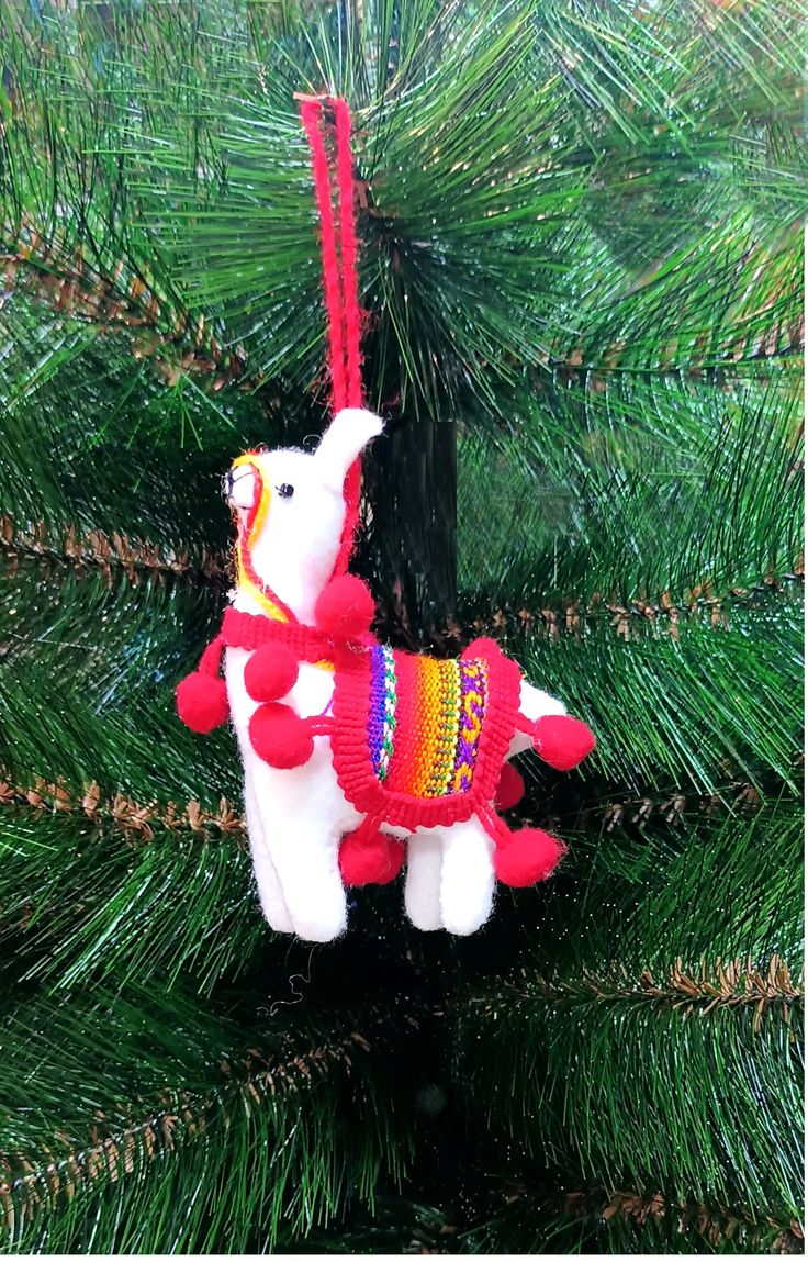 a christmas ornament hanging from a pine tree in the shape of a llama