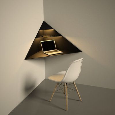 a laptop computer sitting on top of a desk under a triangular shaped wall mounted shelf