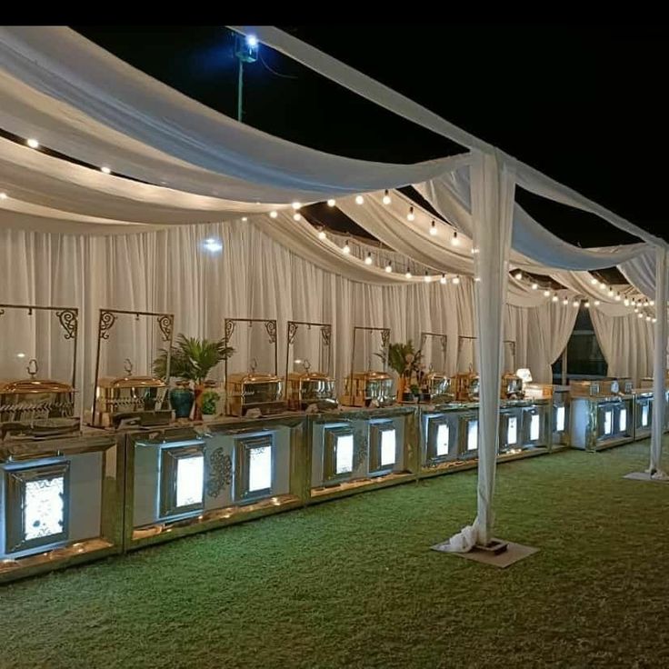 an outdoor event with white draping and lights on the ceiling, chairs and tables are set up in rows