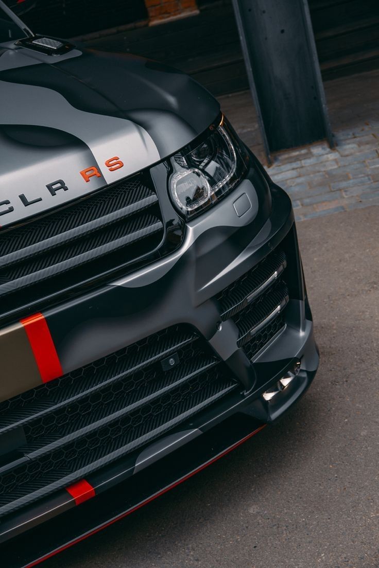 the front end of a black car with red stripes on it's bumpers