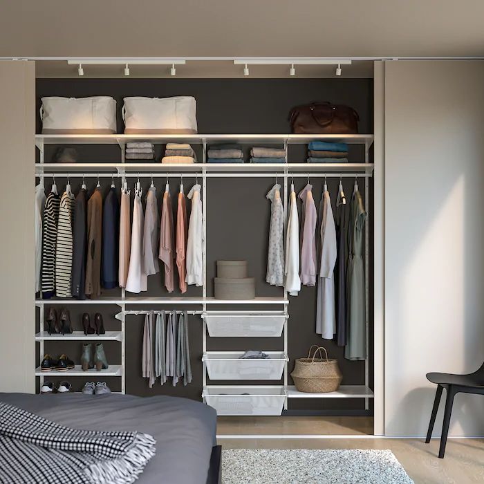 an organized closet with clothes, shoes and other items on the shelves next to a bed