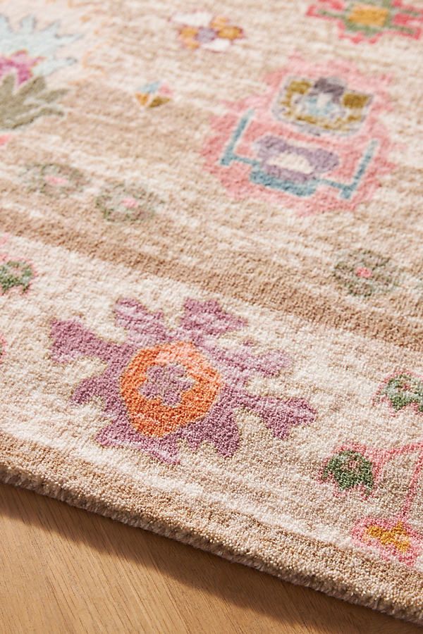 an area rug with flowers on it sitting on a wooden floor next to a vase