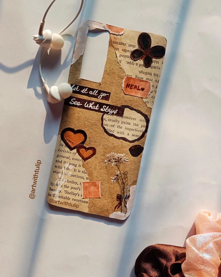 an old cell phone case with hearts and words on it next to a pair of headphones