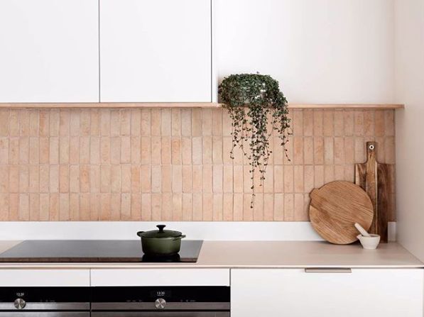 a kitchen with white cabinets and wooden cutting boards on the counter top, along with a potted plant