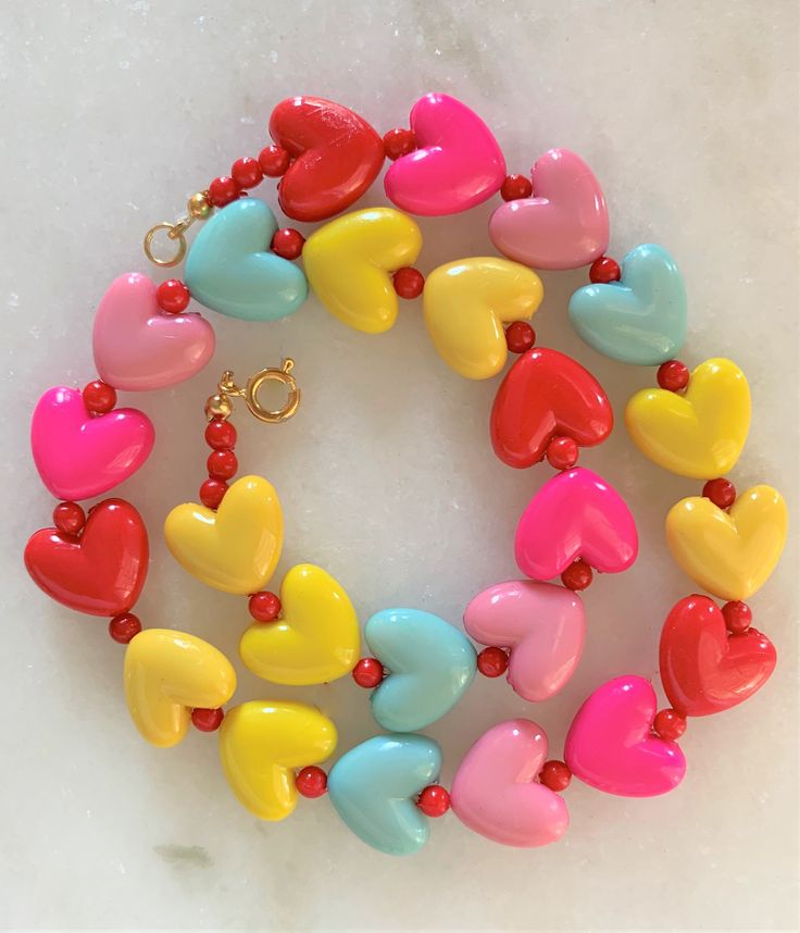 "Kids Brite Multi Colored Plastic Heart Necklace with Red Mini Spacer Beads Gold Tone Spring Ring Clasp Closure Brite Multi Hearts are Red, Hot Pink, Pink, Aqua, Yellow Hearts Measure 5/8\" Wide Necklace Measures 15\" Imported COMPLIMENTARY DOMESTIC SHIPPING" Valentine's Day Playful Beaded Jewelry, Playful Jewelry With Heart Beads, Playful Heart Beads Jewelry, Playful Heart-shaped Colorful Beads Jewelry, Playful Colorful Jewelry With Heart Beads, Fun Multicolor Jewelry For Mother's Day, Playful Round Beads Jewelry For Valentine's Day, Valentine's Day Gift Beaded Necklaces With Round Beads, Playful Valentine's Day Jewelry With Round Beads