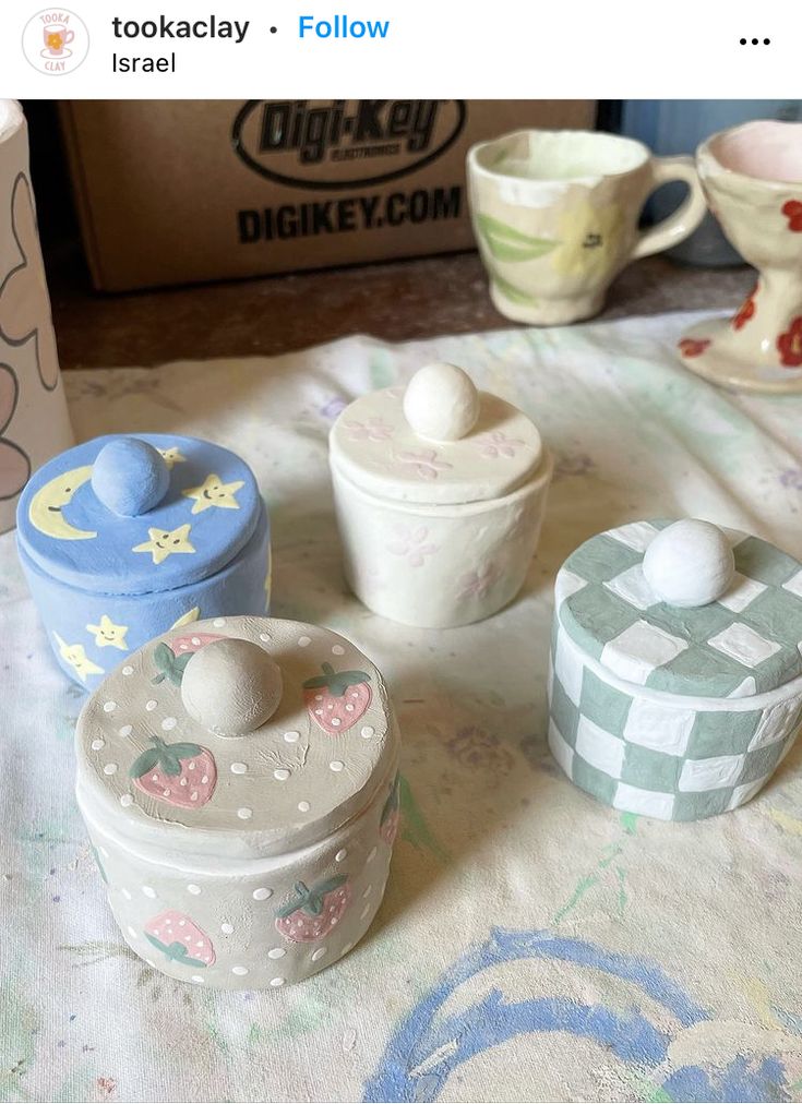 there are many small containers on the table with teacups and cups around them