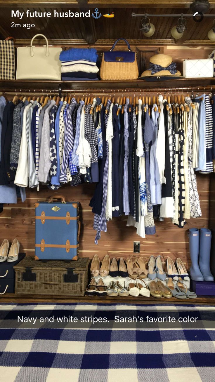 a closet filled with lots of clothes and shoes next to a blue suitcase on top of a wooden floor