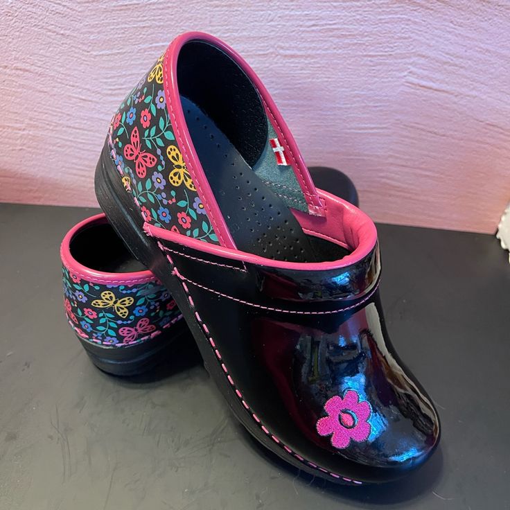 Beautiful, Black Patent Leather Clogs With Floral Back, Pretty Pink Flower On The Front Only Worn Twice Rare Pink Closed Toe Clogs With Removable Insole, Pink Non-slip Closed Toe Clogs, Fun Black Non-slip Clogs, Black Non-slip Fun Clogs, Black Slip-on Clogs With Rubber Heel Cap, Pink Slip-on Clogs With Removable Insole, Functional Black Non-slip Clogs, Black Slip-on Clogs With Ortholite Insole, Dansko Shoes