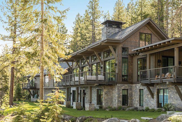 a large house in the woods with lots of windows and balconies on it