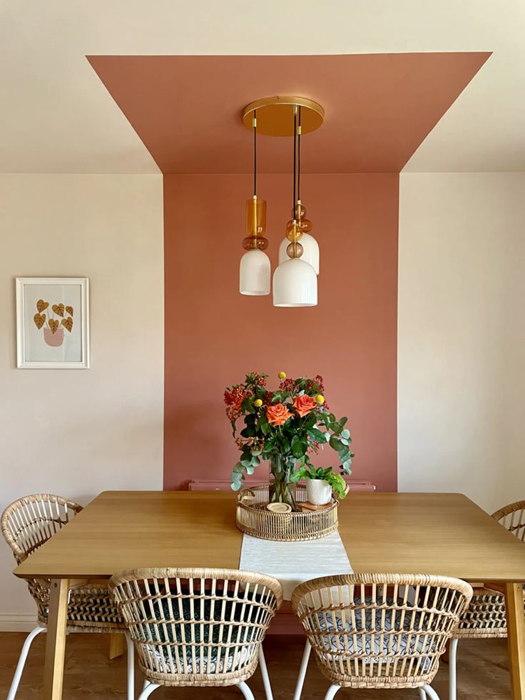 a dining room with pink walls and wicker chairs