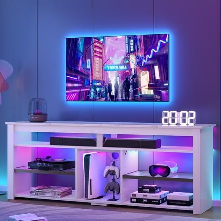 an entertainment center with a large television on it's side and purple lighting in the background