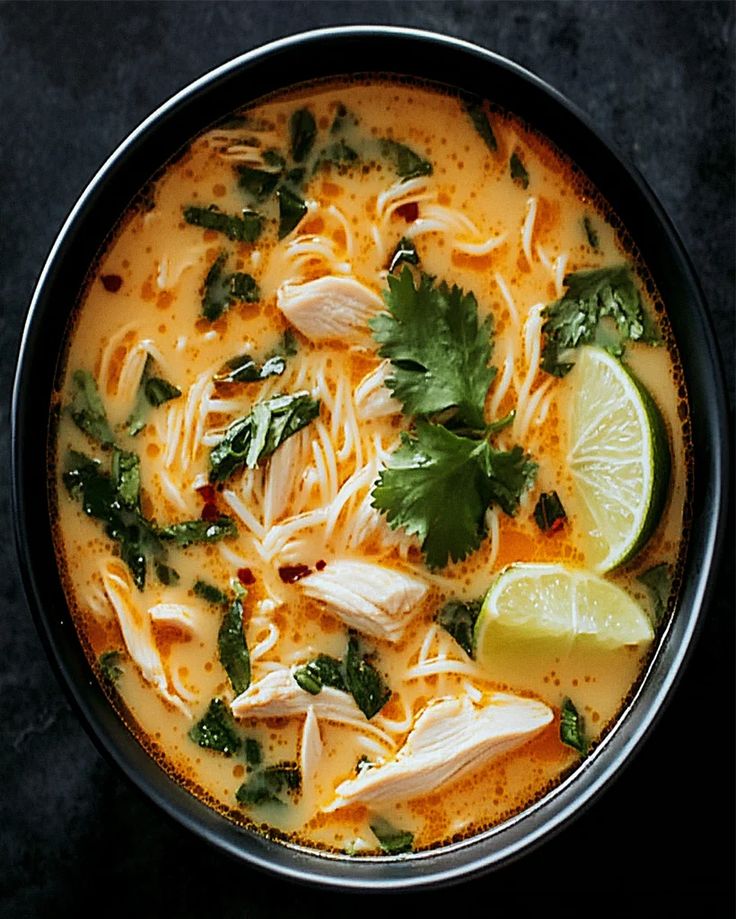 a bowl of chicken noodle soup with cilantro and lime