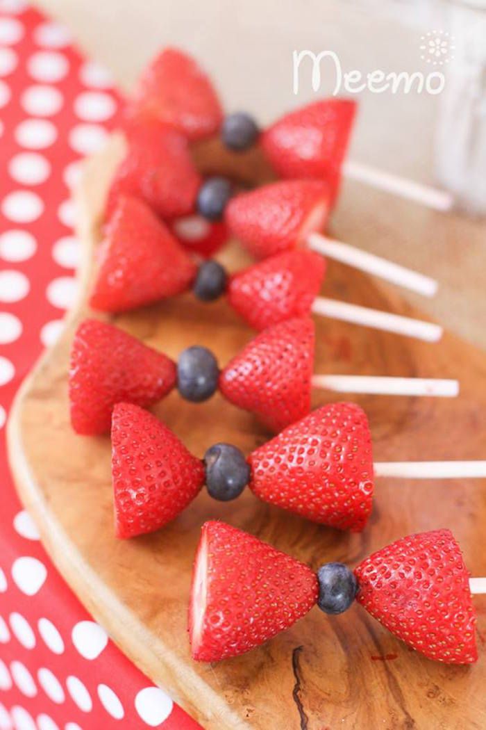 strawberries and blueberries are arranged on sticks