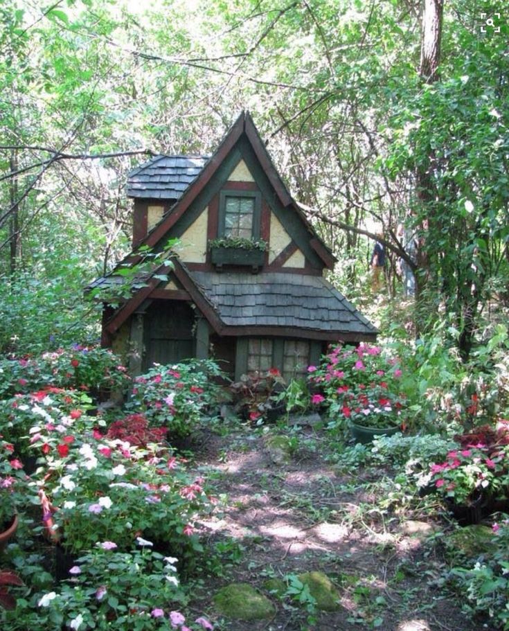 a small house in the woods surrounded by flowers