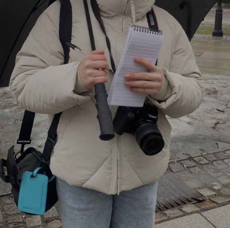 a woman holding an umbrella and looking at a piece of paper with a camera attached to it