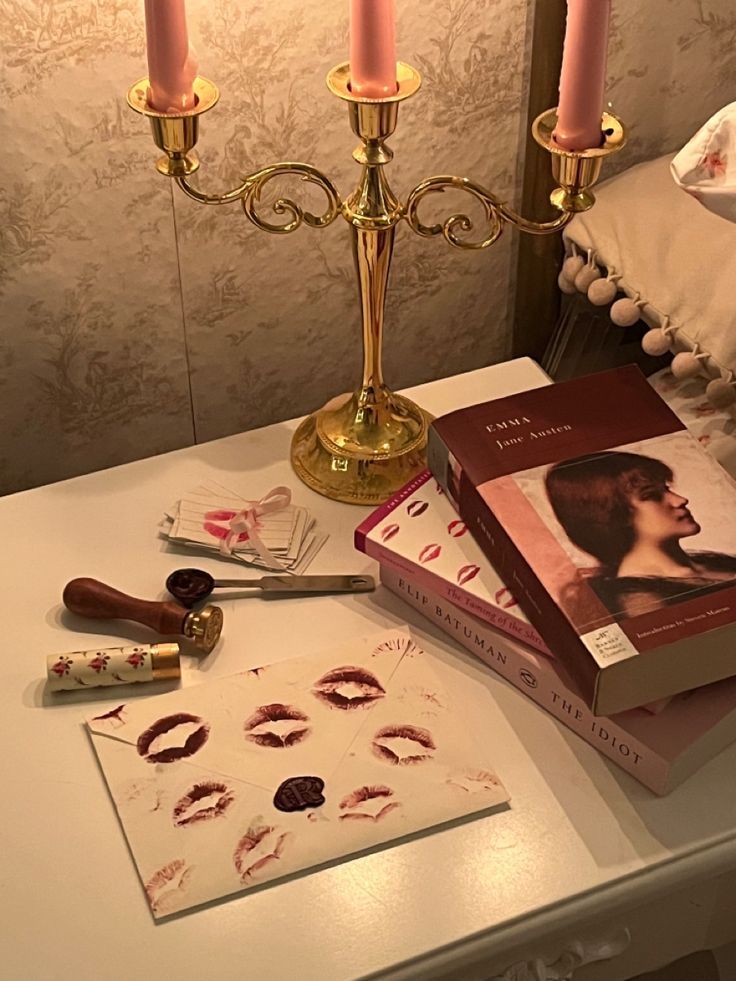 a table topped with books and candles next to a candle holder on top of a white table