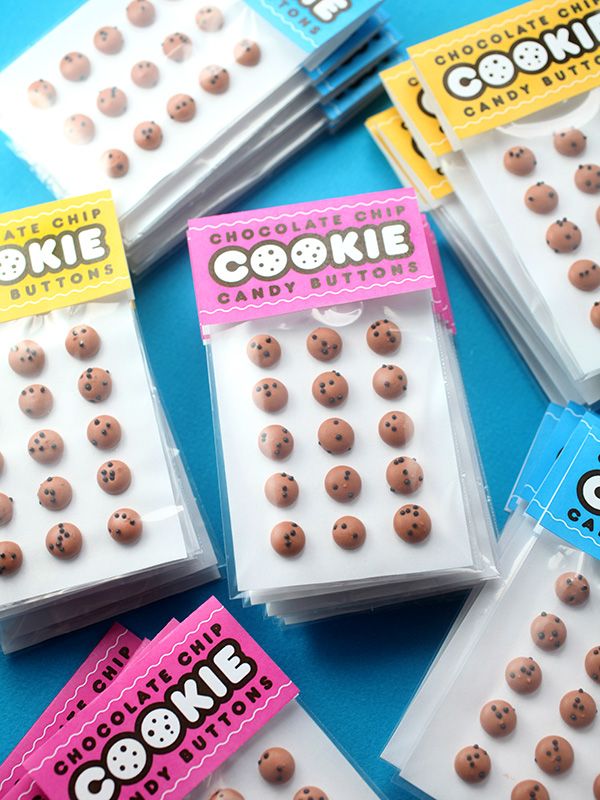 chocolate chip cookie buttons in plastic bags on a blue table with candy stickers attached to them