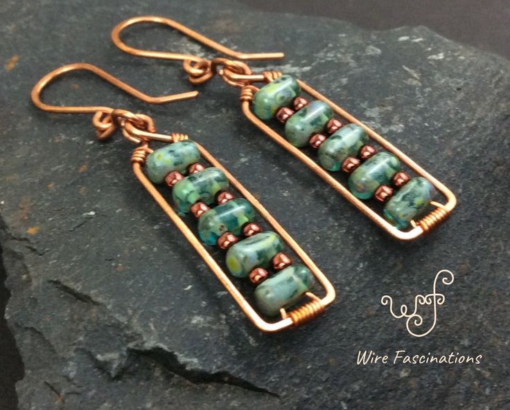 some kind of earrings that are on top of a piece of rock with copper and green beads