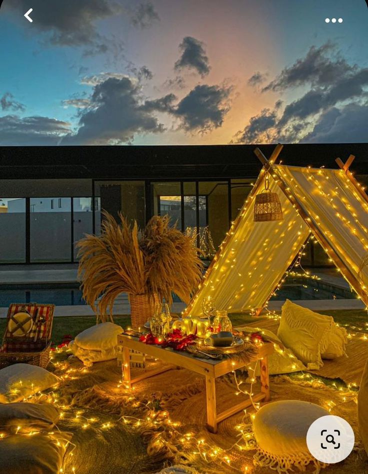 an outdoor area with lights and pillows on the ground, including a teepee tent