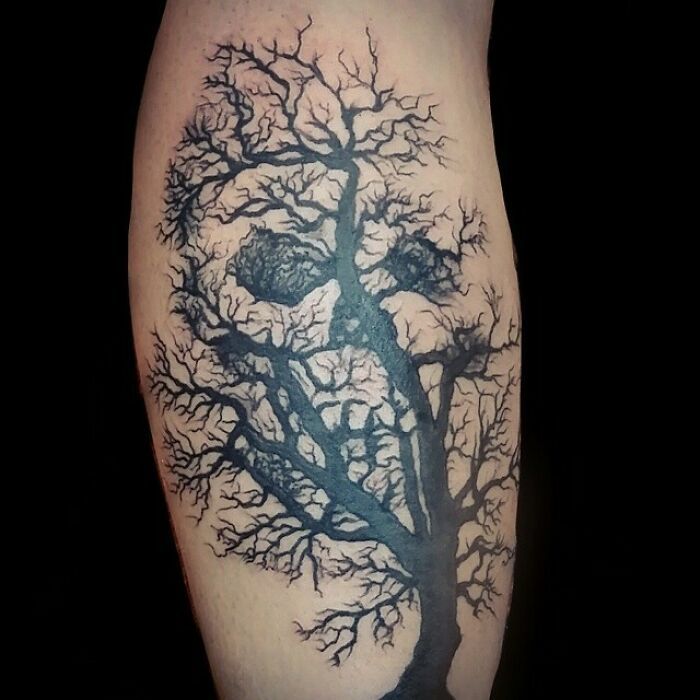 a black and grey tree tattoo on the leg