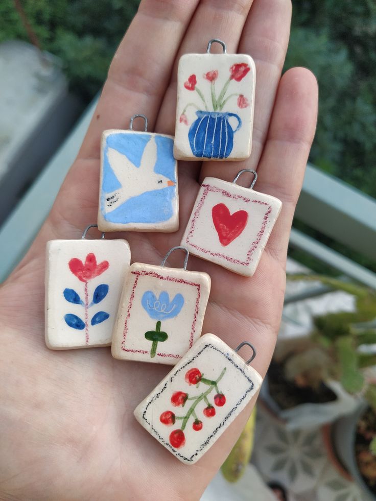 four small ceramic ornaments in the palm of someone's hand with flowers and birds on them